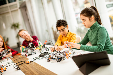 Happy kids programming electric toys and robots at robotics classroom