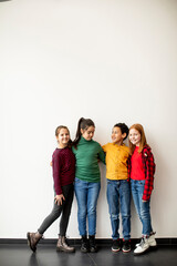 Fototapeta premium Portrait of cute little kids in jeans looking at camera and smiling, standing against white wall