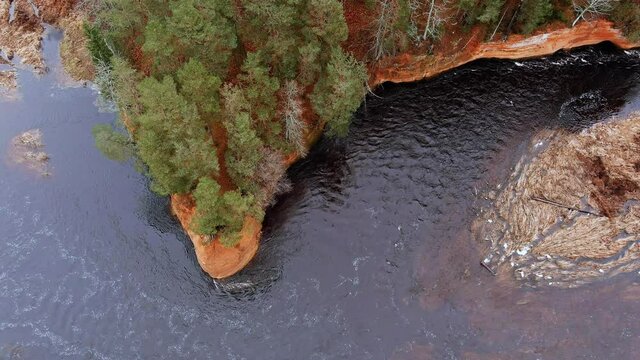 Red sandstone cliffs in the banks of river Salaca during late autumn time, Latvia. Real time drone footage