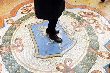 Good luck ritual of stepping on the bull mosaic of the Galleria Vittorio Emanuele II in Milan, Italy