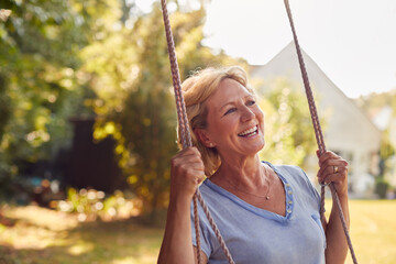 Carefree Smiling Retired Woman Having Fun On Garden Swing