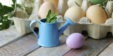 Easter composition of feathers, a cup with eggs, hay and decorations on a wooden surface against the background of a window, the concept of congratulations, postcard