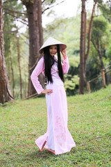 Asian woman, VIetnamese woman in Ao Dai, traditonal ancient female costume with straw hat. Long sleeves and long dress with white pant