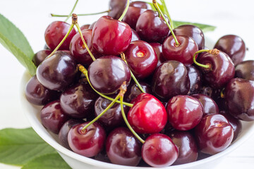 Cherry berries in a bowl on a white background. Fresh cherries. The concept of a healthy diet and support for local producers. Close-up. Top view.