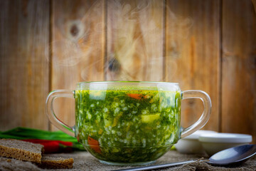 Delicious lunch: vegetarian soup with rice and spinach on a wooden table