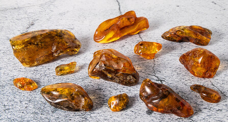 Natural yellow-orange   Baltic amber stones of  different forms and sizes on a light gray plastered surface. Ancient sun stone is healing, love, powers, strength, magic, protection and love.
