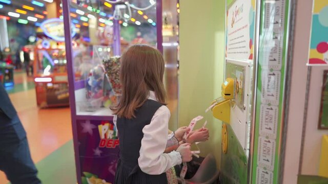 A man helps children to insert coupons into a slot machine.