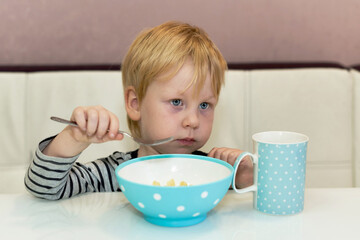 Little boy holding a fork in his hand in front of a plate of food