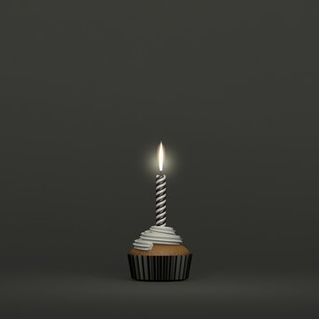 A birthday candle lighting on a creamy muffin cupcake on dark background and dark colors and space for text