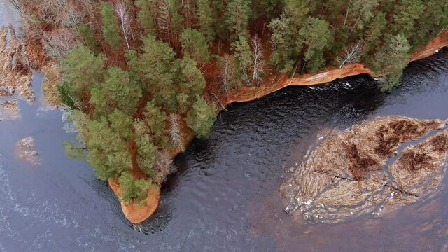 Red sandstone cliffs in the banks of river Salaca during late autumn time, Latvia. Real time drone footage