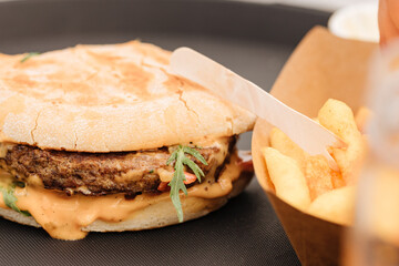 Burger on a black table next to french fries