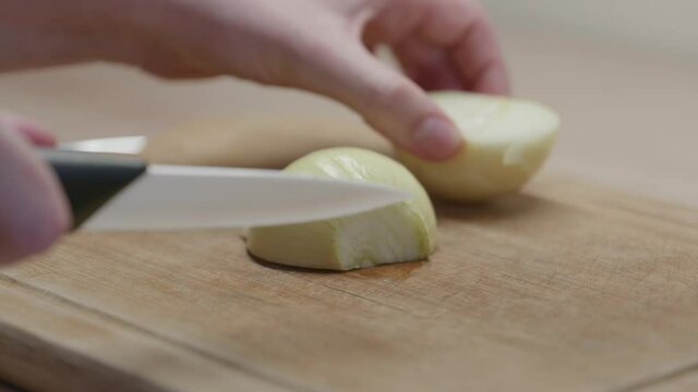 Une femme qui d&eacute;coupe un oignon sur une planche