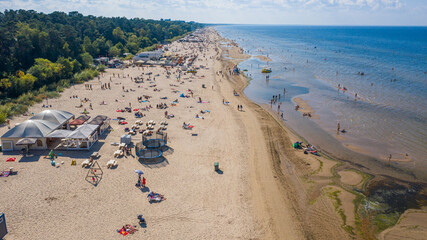 Dzintari, Jurmala ,Latvia, Baltics. Aerial view photo from flying drone panoramic to Dzintari sandy beach full of people sunbathing and swimming in the Baltic Sea on a hot and sunny summer day. (Serie