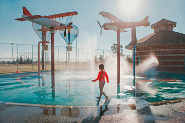 Cute adorable Caucasian funny girl playing on splash pad playground on summer day. Seasonal water sport recreational activity for kids outdoors. © anoushkatoronto