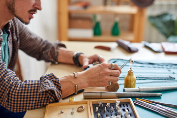 male jeweler using flame torch to solder a ring, making durable jewelry. in workshop