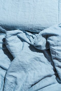 Flatlay of blue linen bed cloths and pillow, morning concept