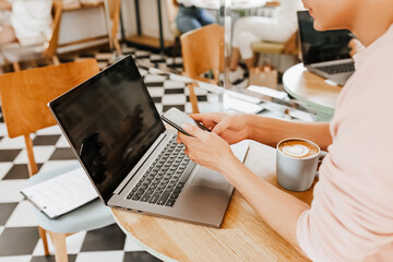 Happy business man sitting at cafeteria with laptop and smartphone. Businessman texting on smart phone while sitting in a cafe, working and checking email on computer