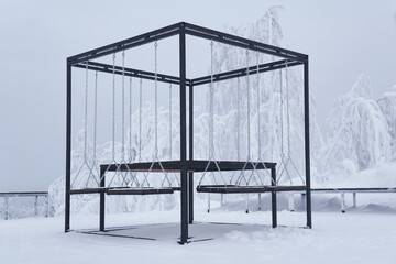 outdoor furniture - picnic table with swing benches - in a frosty winter park