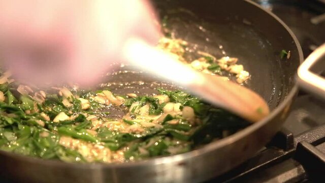 pan-fried wild garlic with seeds and onion in slowmotion 