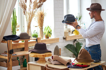 male atelier worker sewing hat in workshop, productive work on new collection in studio.fashion and vogue concept