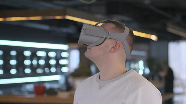 Young man wearing virtual reality headset in modern interior.