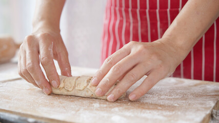Whole wheat bread from homemade whole grain dough made by woman with red apron. Healthy pastry with many grains.
