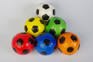 Multi-colored toy soccer balls on a light background.
