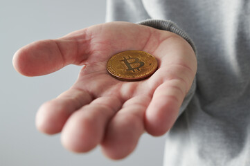 Hand offering Bitcoin cryptocurrency coin