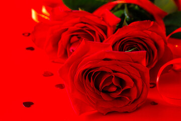 Red roses and decor in the shape of a heart on a red background.