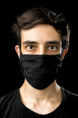 Young man wearing black face mask. Pandemic coronavirus covid-19 quarantine period concept. Black background studio