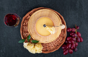 Gourmet tasty cheese Tete de Moine, a glass of red wine and a bunch of grapes, top view, shallow depth of sharpness