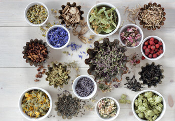 Assortment of dried herbs: blossom, root and seed, flat on the table, lavender, chamomile, lime, rose, cornflower, meadowsweet, thyme and others overhead top view, naturopathy and medicine concept