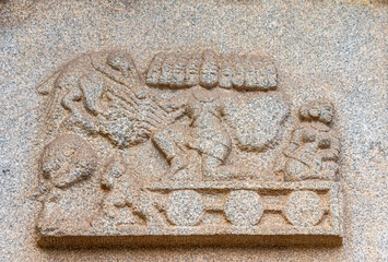 Hampi, Karnataka, India - November 4, 2013: Hazara Rama Temple. Closeup of beige stone sculptures of multi-headed Ravana on cart with woman.