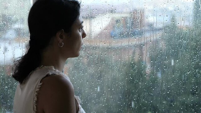 sadness, depression-young woman looks out the window in a rainy day
