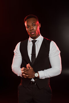 stylish african american man in formal wear with vest standing on black