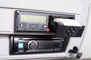 Digital tachograph with open printer and visible roll of paper. Car radio bellow and telephone microphon. Paper Replacement in truck digital tachograph. - obrazy, fototapety, plakaty