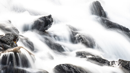 Fototapeta na wymiar White Rushing Water Flowing Over Exposed Jagged Rocks