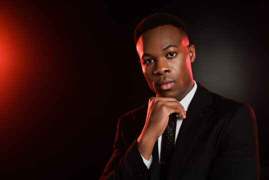 african american man in formal wear looking at camera on black