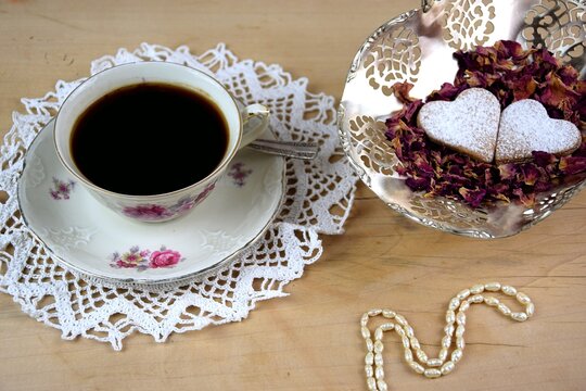 Kawa i dwa serduszka ciasteczka w płatkach róż, drewniane tło, perełki, śniadanie na walentynki