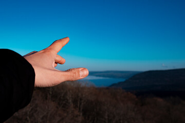Hand pointing to the sky. Beautiful mountain landscape.