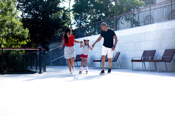 Parent teaching the kid rollerblading. The girl dressed protective helmet and rollers for skating....