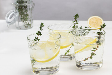 Three glasses with lemon and sprig of thyme in glass