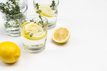 Lemon drink in glass. Thyme sprigs in glass. Lemons on table and in ceramic bowl
