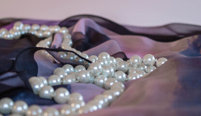 Pearls on a violet silk scarf background, close up