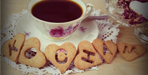 Fototapeta KOCHAM napis z ciasteczek przy kawie, romantyczne Walentynki, naturalne tło, styl retro, vintage obraz