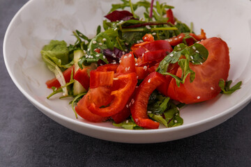 Vegan Spring Salad. Tomato, lettuce, dressing, bell peppers and avocados. Fork with vegetables and salad.