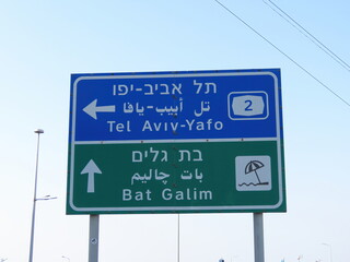 Road signs with the inscriptions Tel Aviv-Yafo and Bat Galim beach in three languages (English, Arabic, and Hebrew) close-up in Haifa, Israel.