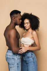 African american man hugging woman with closed eyes on beige