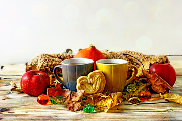 Autumn  still life tea. Yellow cup of tea, homemade cookies surrounded by autumn leaves, a scarf, pumpkins and apples on a wooden table, copy space
Cozy style