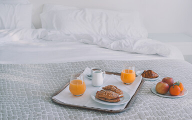 healthy breakfast on a hotel bed. The background is clear and smooth. There is a lot of colorful fruit and juice.